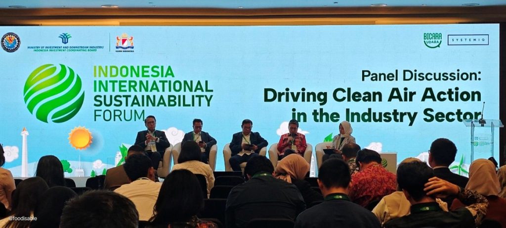Four panelists, one host seated on stage during a discussion on Driving Clean Air Action in the Industry Sector at the Indonesia International Sustainability Forum, while the audience listens attentively